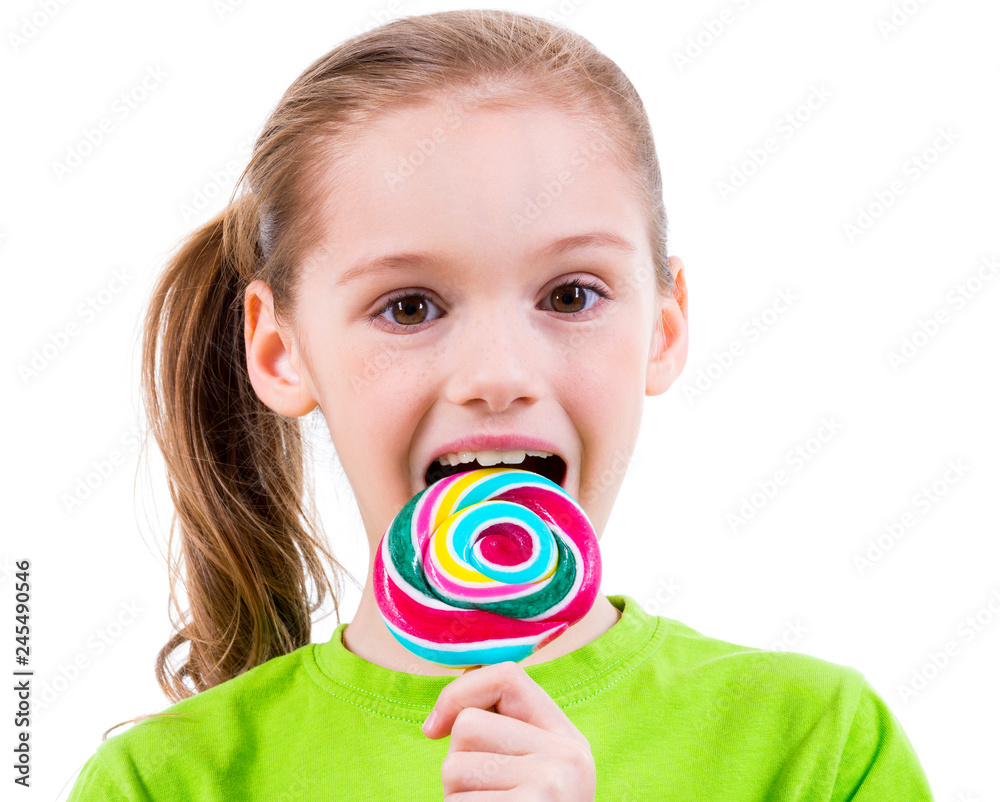 Smiling little girl in green t-shirt eating colored candy.