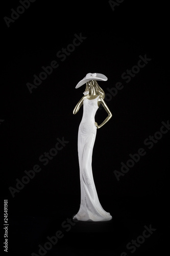 White porcelain figurine of a woman in a hat on a black background