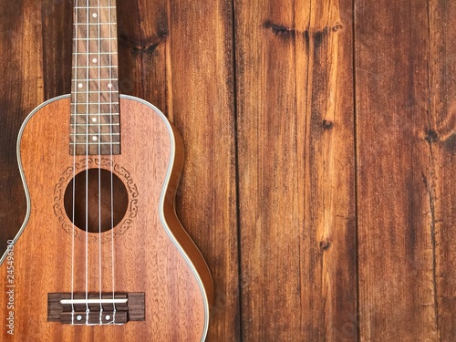 A ukulele on brown wooden background.
