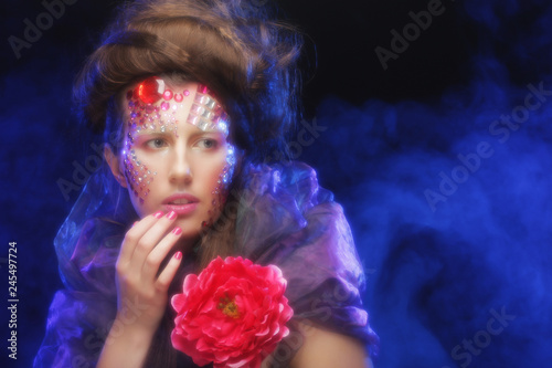  young woman with creative make up holding flowers