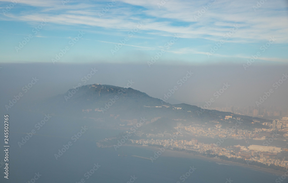 Aerial view of coastal city disappearing into thick layer of heavy smog and air pollution