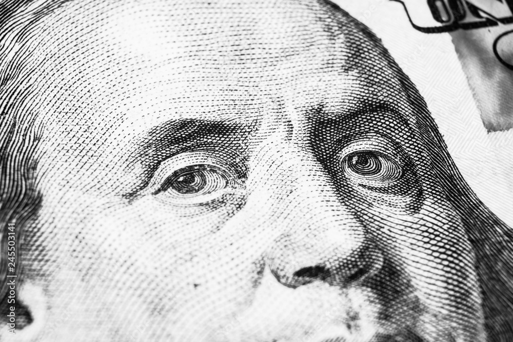 Close up view Portrait of Benjamin Franklin on the one hundred dollar bill. Background of the money. 100 dollar bill with Benjamin Franklin eyes macro shot. Black and white