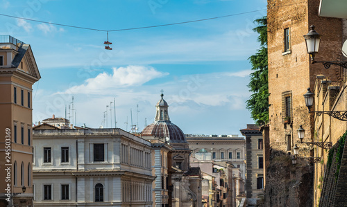 Sneakers hanging on the wire on street in front of old buildings in historical center of Rome, Italy