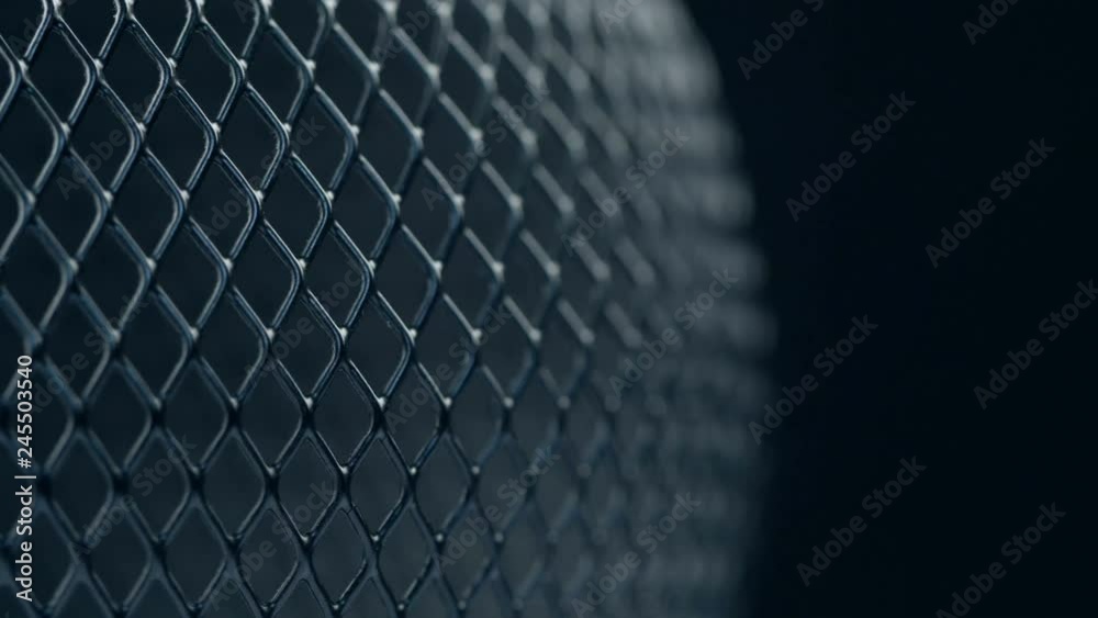 Black metal grid rotating on dark background. Close up macro 4k footage.