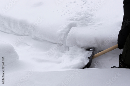 Man cleans snow with a shovel in winter