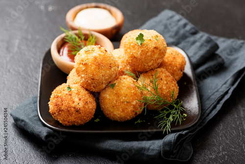 Potato croquettes - mashed potatoes balls breaded and deep fried, served with different sauce. photo