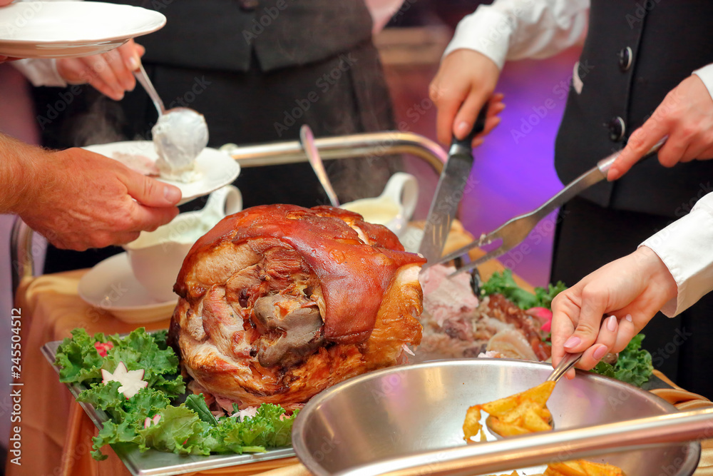 waiter serves roasted meat and baked potatoes at the party or wedding reception
