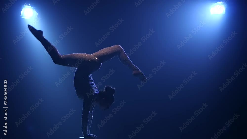 Gymnast makes various movements while standing on it. Smoke blue background. Slow motion. Silhouette Gymnast makes various movements while standing on it. Smoke blue background. Slow motion. Silhouette