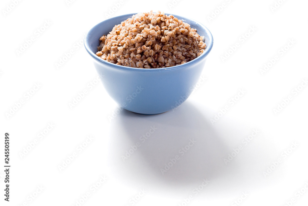Boiled buckwheat in blue deep plate on white background with shadow Boiled buckwheat in blue deep plate on white background with shadow