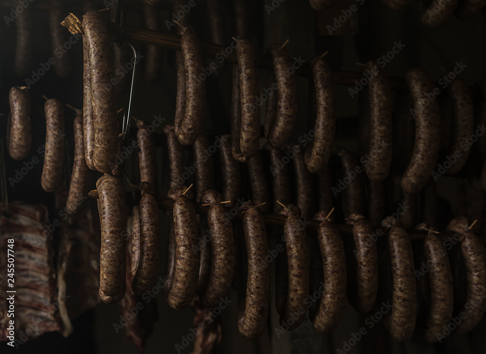 Home made sausages are hanging in a smoked room