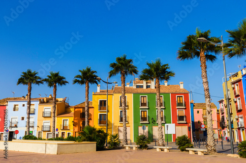 Beautiful promenade with flowers, palm trees, trees against the colorful houses of the ancient city of Villajoyosa Spain.