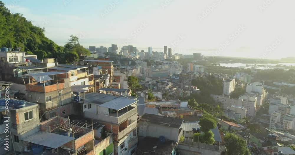 Sunrise aerial flying around hilltop favela with downtown Rio de Janeiro high rise buildings in the background Sunrise aerial flying around hilltop favela with downtown Rio de Janeiro high rise buildings in the background