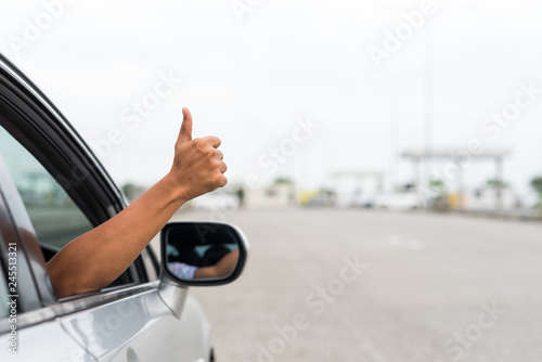 Man hand showing thumbs up while driving car.