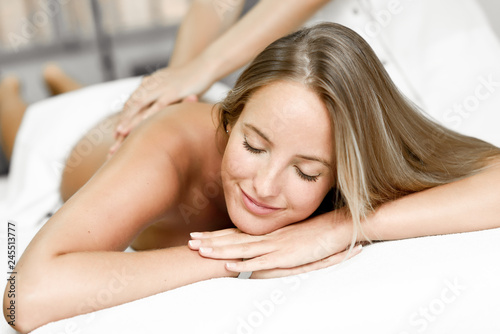 Young blonde woman having massage and smiling in the spa