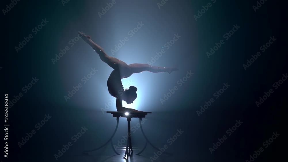 Acrobat girl executes tricks . Smoke background. Slow motion. Silhouette Acrobat girl executes tricks . Smoke background. Slow motion. Silhouette
