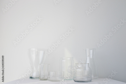 Collection of empty glass vases on white table sheet on white background in natural light