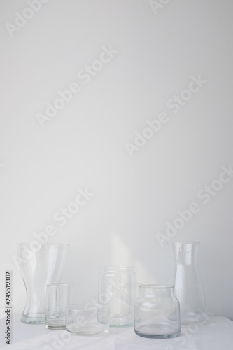 Collection of empty glass vases on white table sheet on white background in natural light
