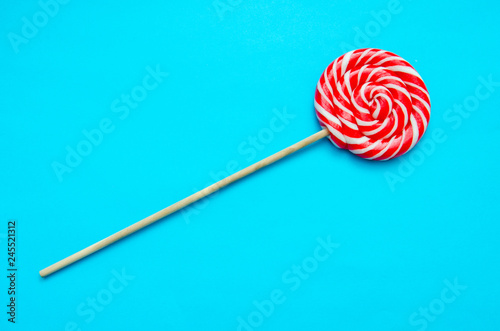 beautiful red and white striped lollipop on a blue background