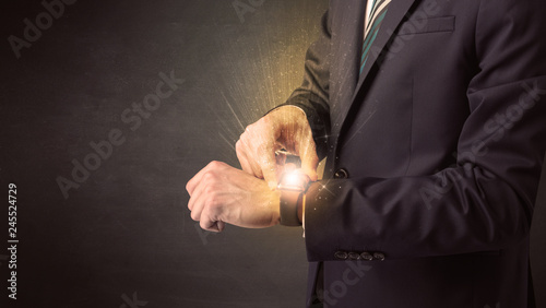 Businessman wearing smartwatch with shiny rays on it.