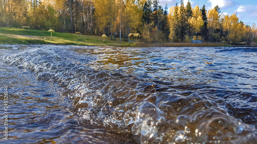 Northern nature. Autumn. Storm in Sunny weather. Wave to lake forest on the background of autumn forest