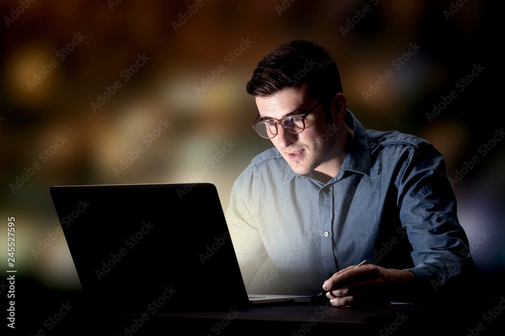 Young handsome businessman working late at night in the office Young handsome businessman working late at night in the office