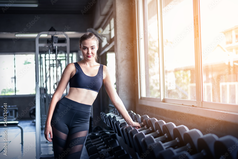 Young attractive fitness caucasian  girl posing near dumbbell weights in gym .Sporty woman showing her well trained body . Well developed muscles strong training .Workout training healthy concept.