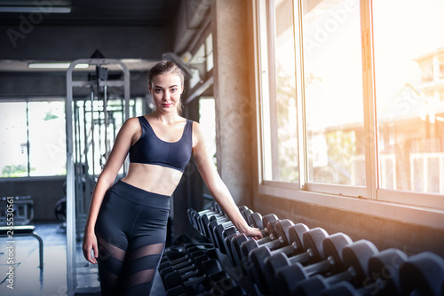 Young attractive fitness caucasian girl posing near dumbbell weights in gym .Sporty woman showing her well trained body . Well developed muscles strong training .Workout training healthy concept.