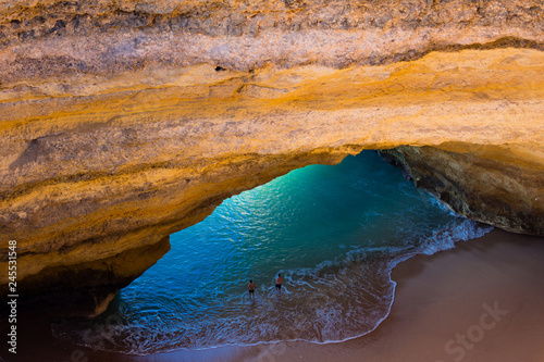 Aerial view of the impressive Benagil sea cave, a coastal sandstone cave. Two men in the water.