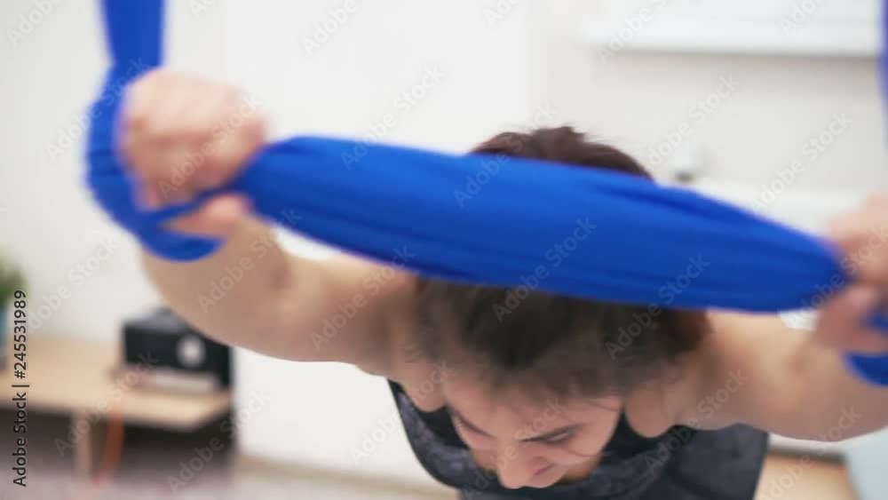 Beautiful young girl stretching fitness hammock. 