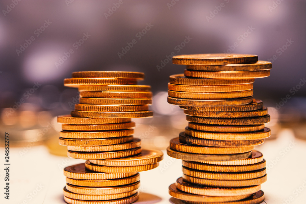 Two stacks of gold coins, one leaning slightly, on a white surface. Two stacks of gold coins, one leaning slightly, on a white surface.