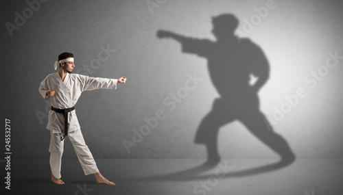 Young karate man confronting with his own shadow  © ra2 studio