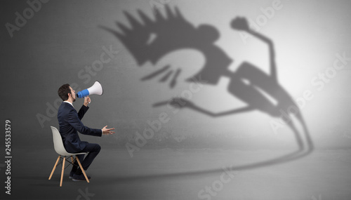 Young businessman staying and negotiate with a monster shadow 