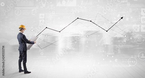 Engineer with construction helmet holding a plan and standing with graphs, charts and reports on the background