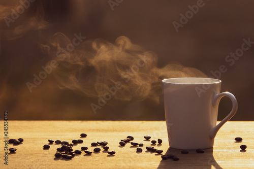 Hot coffee cup with organic coffee beans on the wooden table and blurred background with copy space