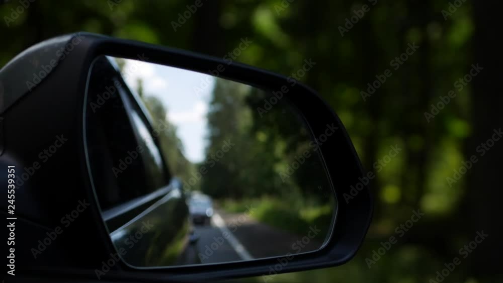 View out the rearview mirror as car drives on country road. 4K