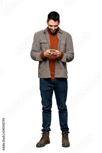 Full-length shot of Handsome man with beard sending a message with the mobile on isolated white background