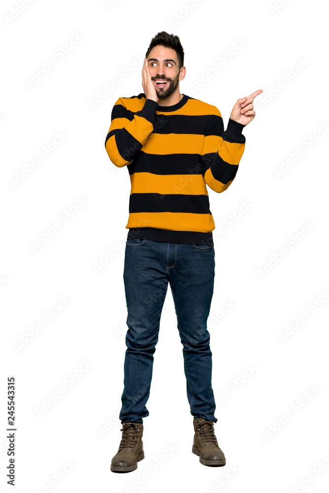 Full-length shot of Handsome man with striped sweater pointing up and surprised on isolated white background Full-length shot of Handsome man with striped sweater pointing up and surprised on isolated white background