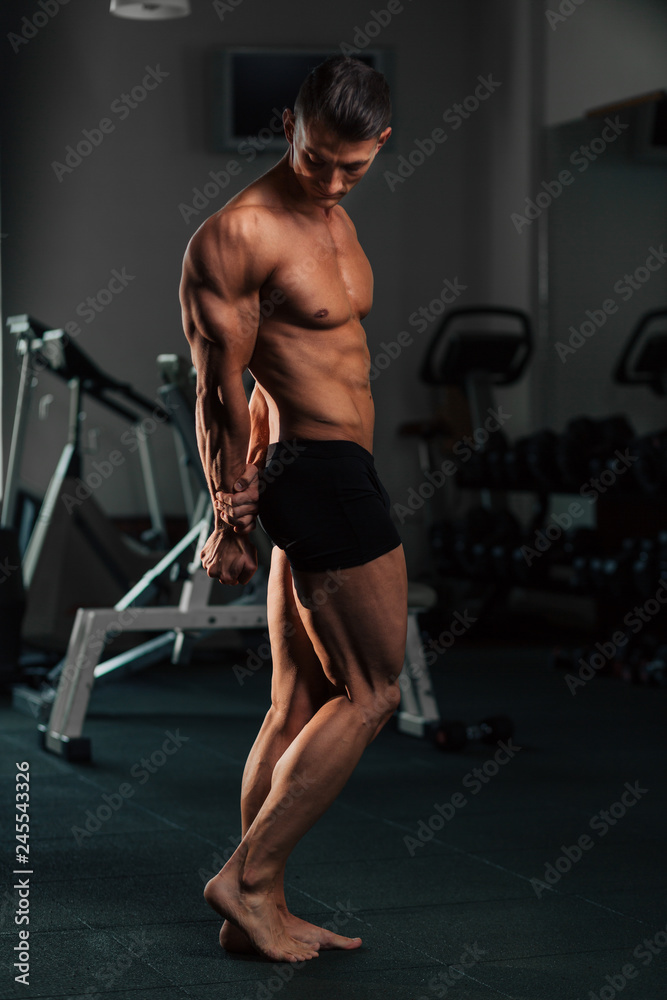 Young fit man doing bodybuilding competition poses