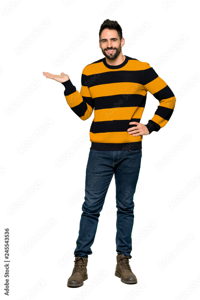 Full-length shot of Handsome man with striped sweater holding copyspace imaginary on the palm to insert an ad on isolated white background Full-length shot of Handsome man with striped sweater holding copyspace imaginary on the palm to insert an ad on isolated white background