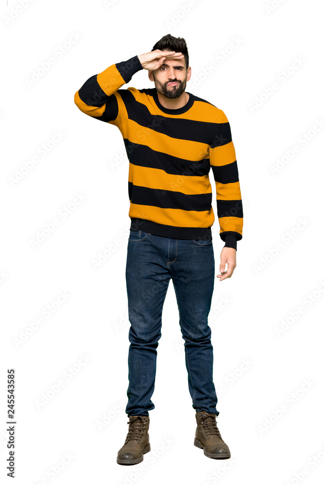 Full-length shot of Handsome man with striped sweater looking far away with hand to look something on isolated white background Full-length shot of Handsome man with striped sweater looking far away with hand to look something on isolated white background