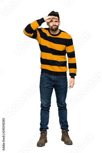 Full-length shot of Handsome man with striped sweater looking far away with hand to look something on isolated white background