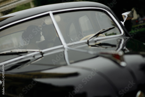 Beautiful happy young bride and groom looking from retro auto © wolfhound911