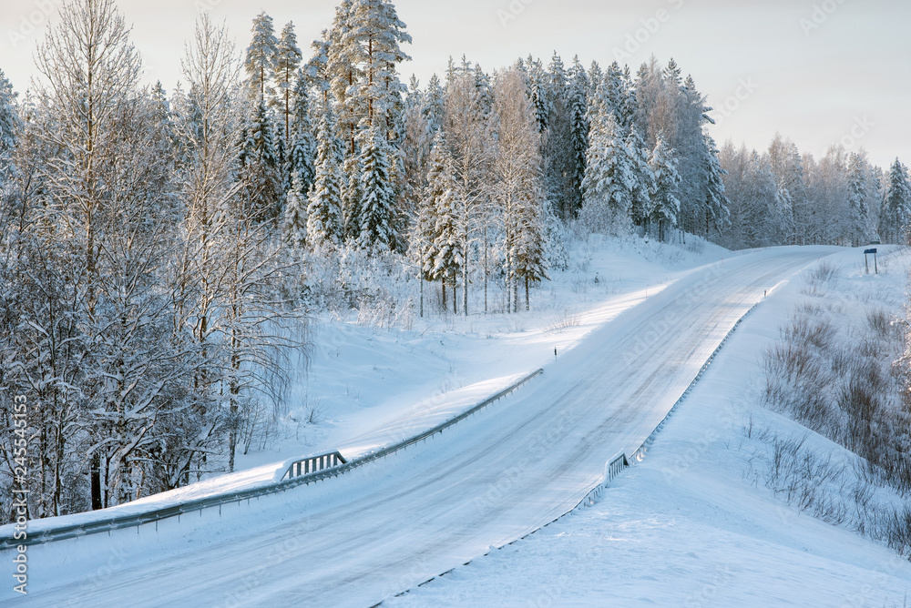 Snowy road winding through winter forest landscape in Eastern Finland