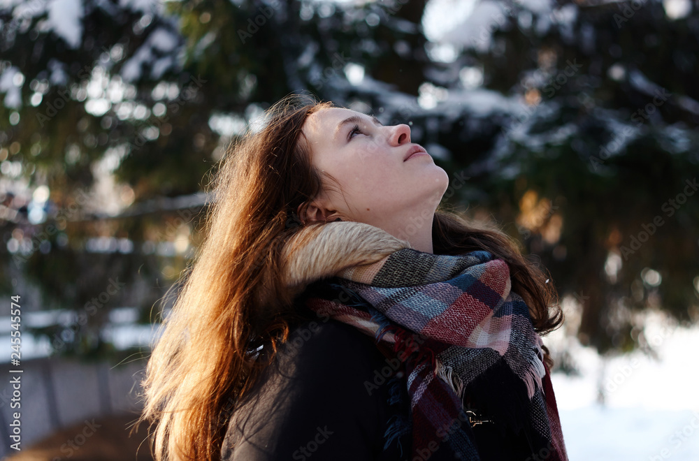 Beautiful girl looking at the sky standing in winter weather in the forest Beautiful girl looking at the sky standing in winter weather in the forest