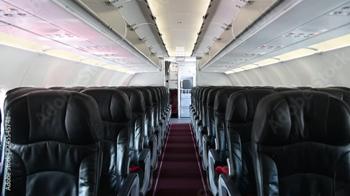 4K Interior of commercial airplane cabin with black and red passenger seats.