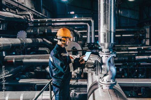 Foto Portrait of young Caucasian man dressed in work wear using tablet while standing in heating plant