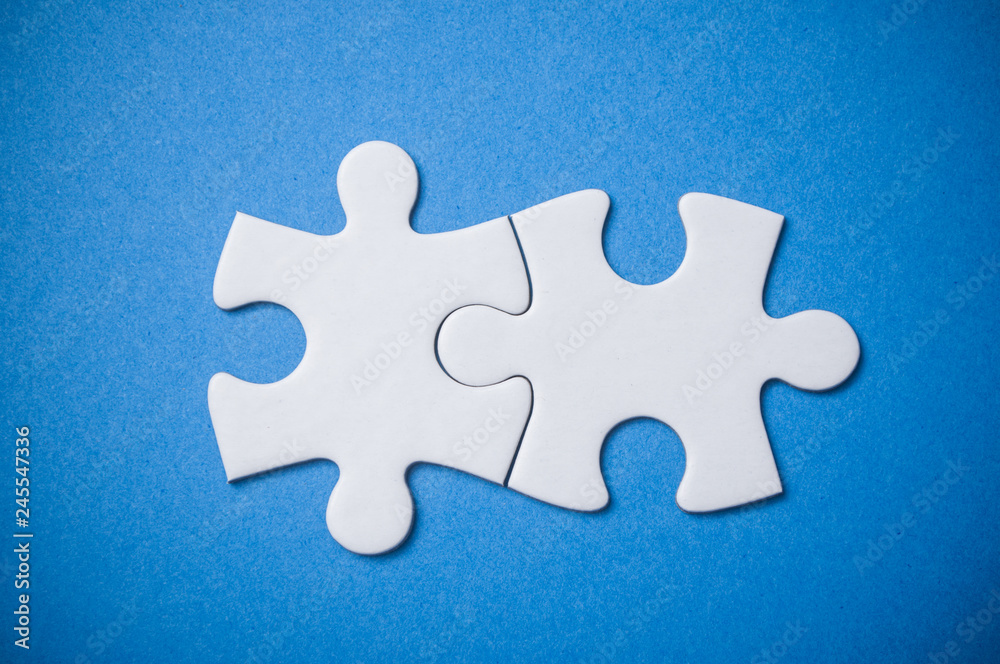 Closeup of Two connected jigsaw puzzle pieces on blue background. The concept of finding the right solutions in teamwork. Closeup of Two connected jigsaw puzzle pieces on blue background. The concept of finding the right solutions in teamwork.