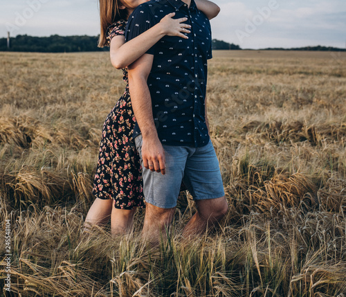 beautiful couple in love standing in the middle of a wheat field in an embrace © Oleksii