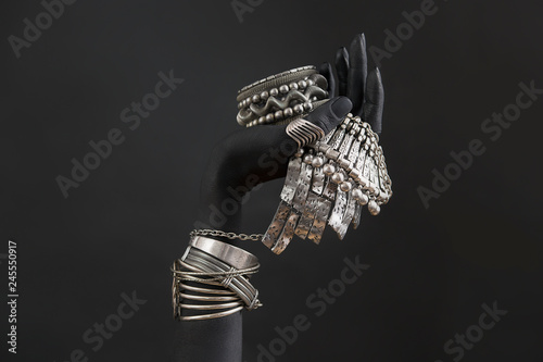 Black woman's hand with Silver jewelry. Oriental Bracelets on a black painted hand.