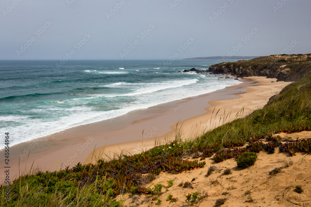 Long empty sandy beach on Atlantic ocean coast, Atlantic Ocean, Rota Vicentina, Alentejo, Portugal. Long empty sandy beach on Atlantic ocean coast, Atlantic Ocean, Rota Vicentina, Alentejo, Portugal.